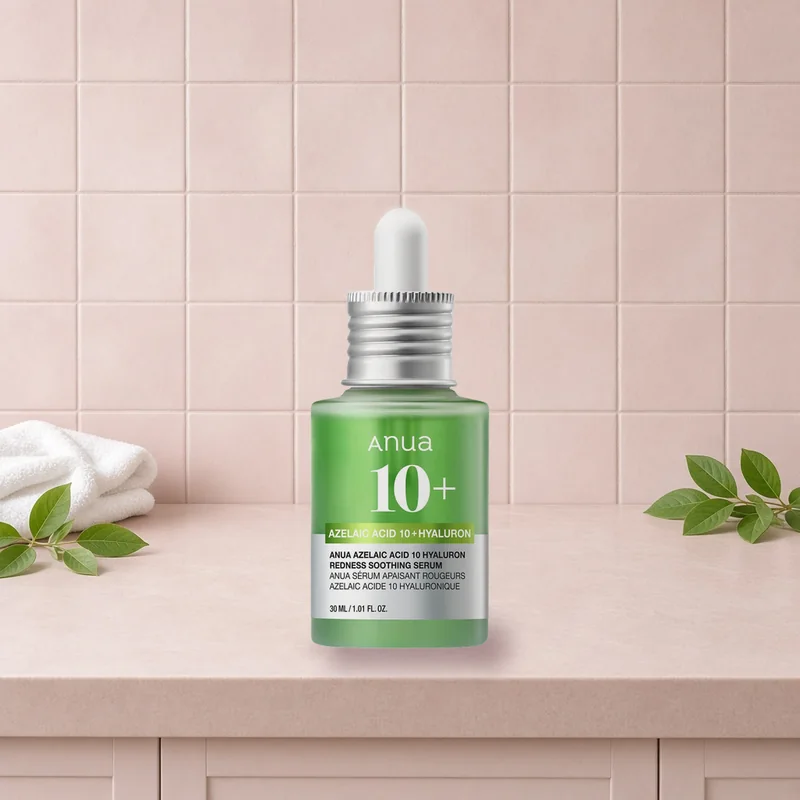 The Anua Azelaic Acid 10 Hyaluron Redness Soothing Serum dropper bottle on a blush tiled vanity with fresh green leaves