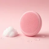 Illustration of a round pink silicone face cleansing brush beside cleanser foam
